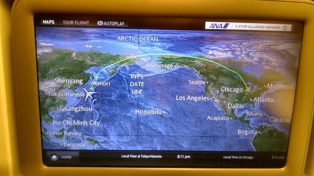 Airplane seatback screen showing map with flight path from Chicago to Tokyo