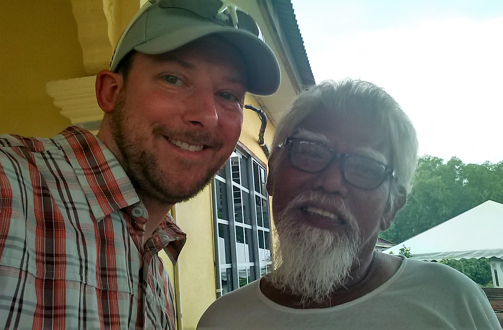 Two people smiling young man with hat older man white beard