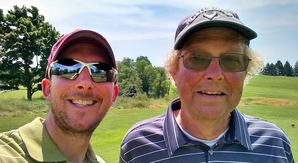 Author and father on a golf course smiling into camera wearing hats and shades