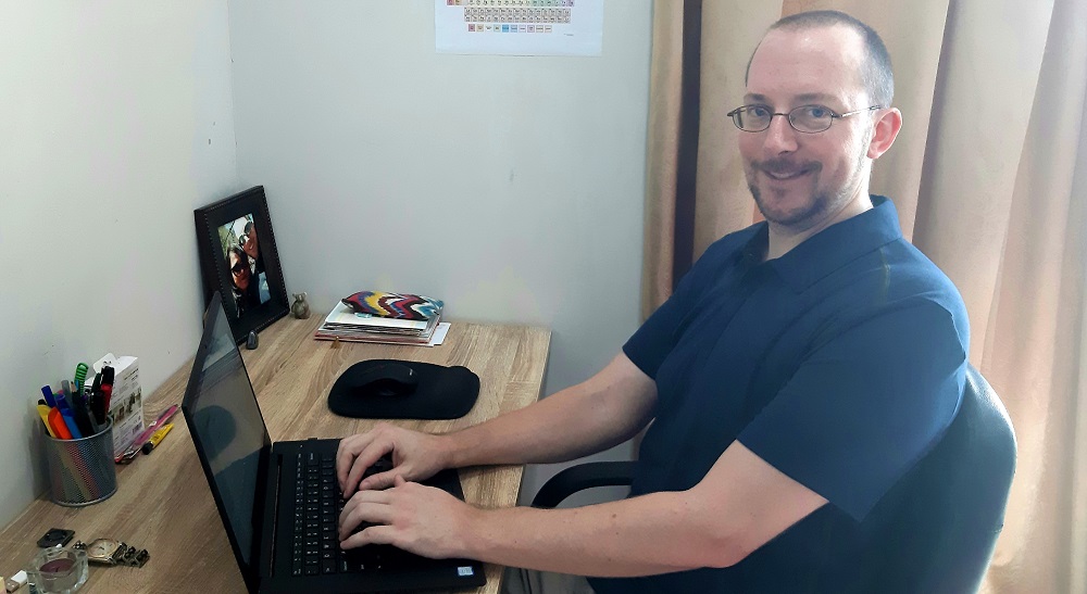 Author smiling working at a laptop