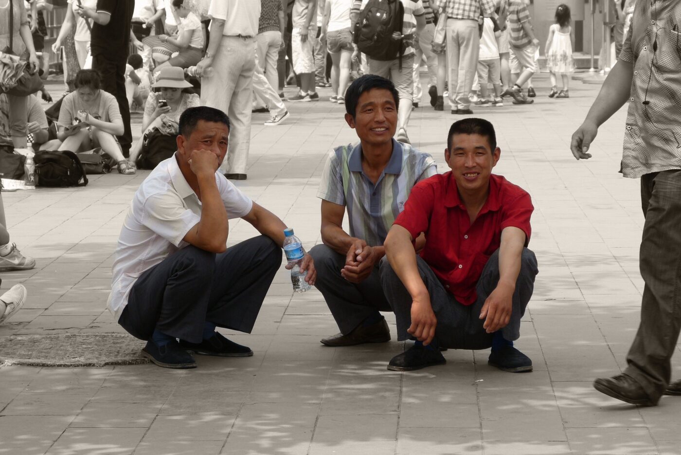 stock photo of three asian men squatting on a public sidewalk