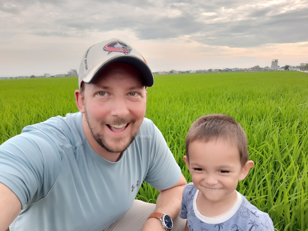 father and son smiling in a green paddy field