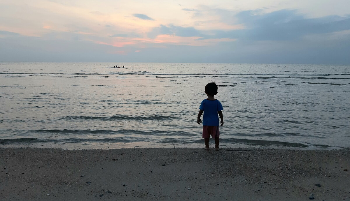 silouette of a small boy on the beach at sunset