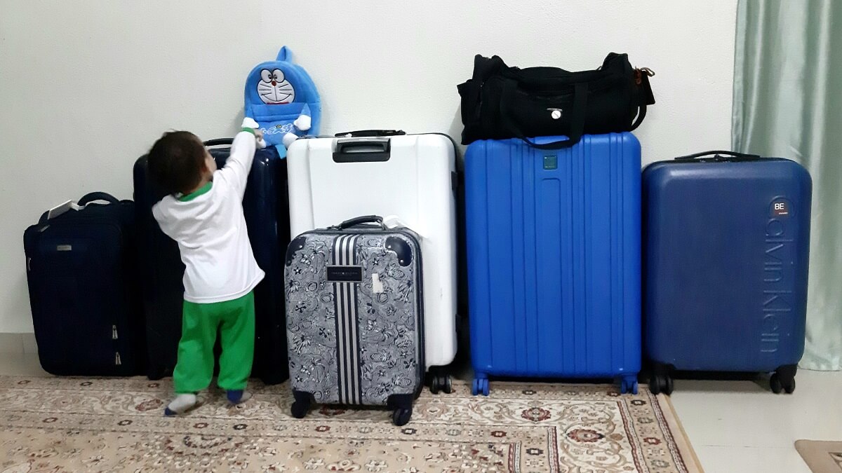 A row of suitcases with a small child in front