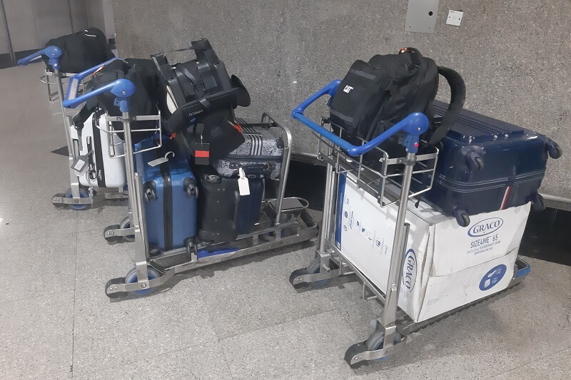 Three handcarts loaded with suitcases and bags