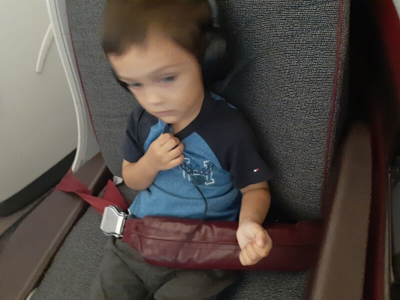 Toddler Adam in airplane seat wearing headphones