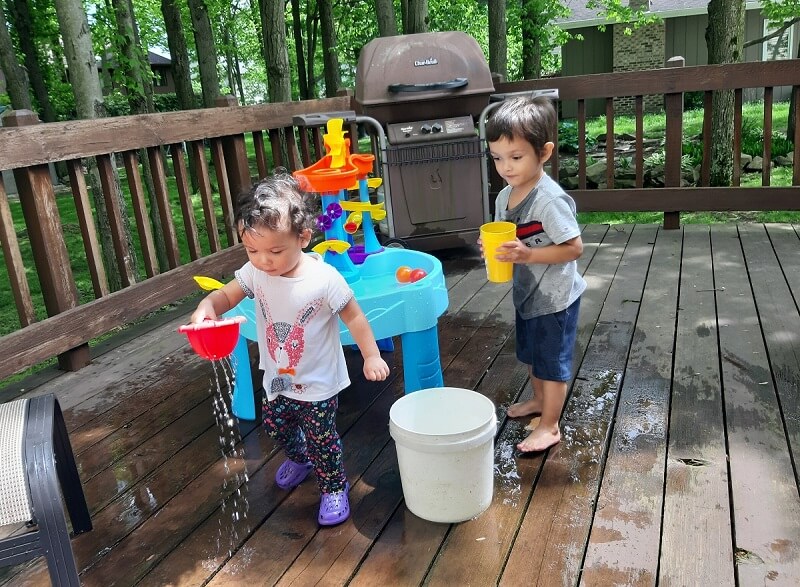 Kids playing with water toys on the deck surrounded by green trees