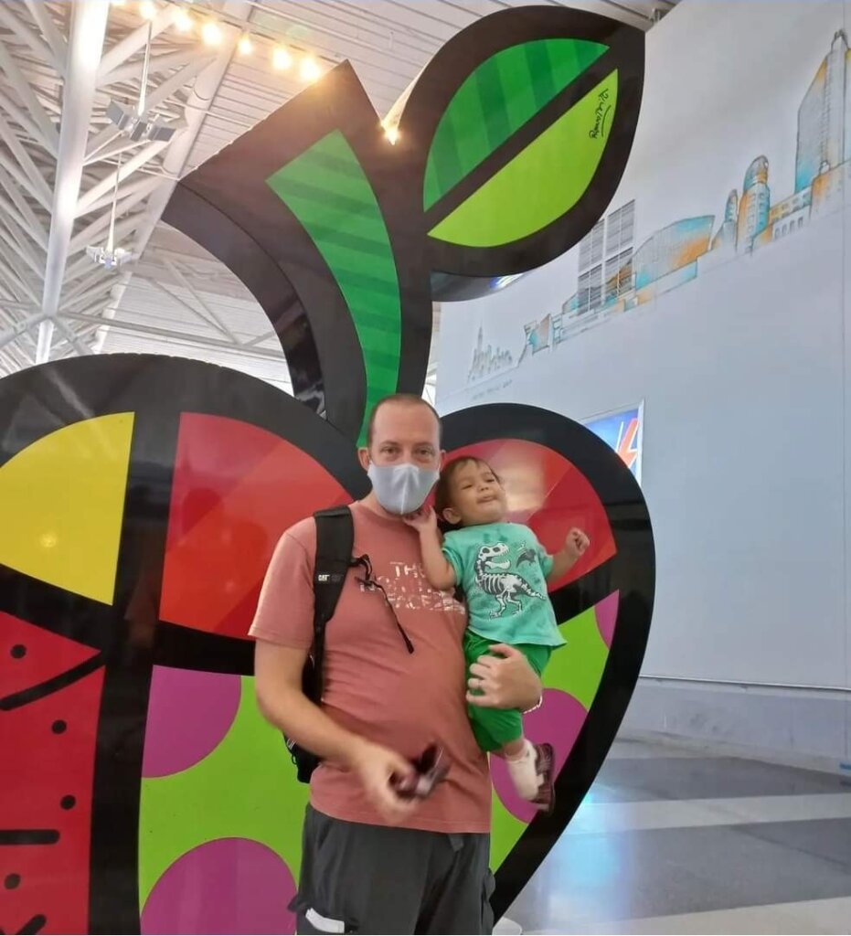 Author holding daughter in front of big apple artwork