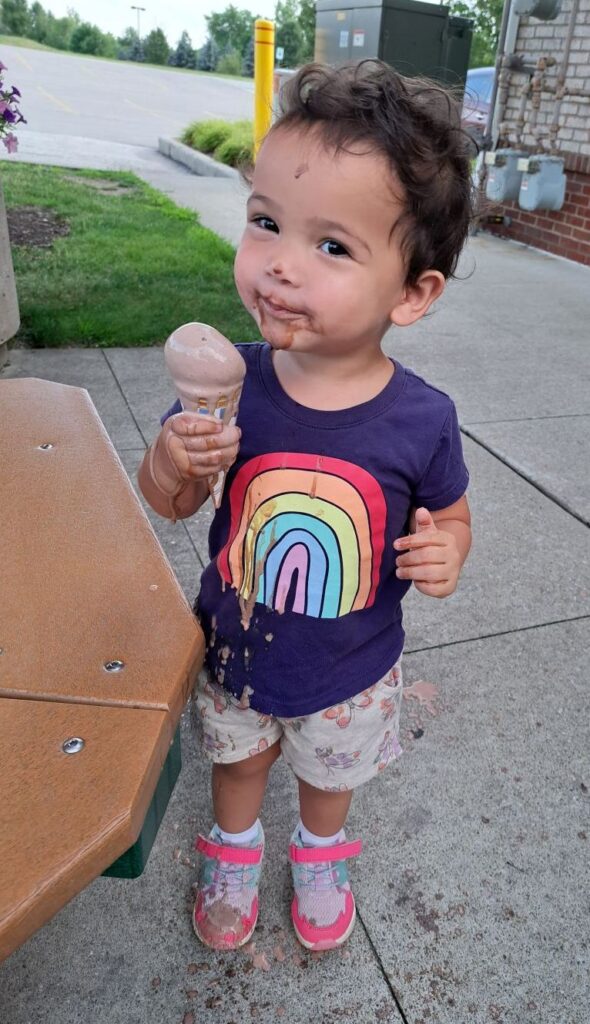 Little girl with an ice cream cone covered in dripping chocolate ice cream