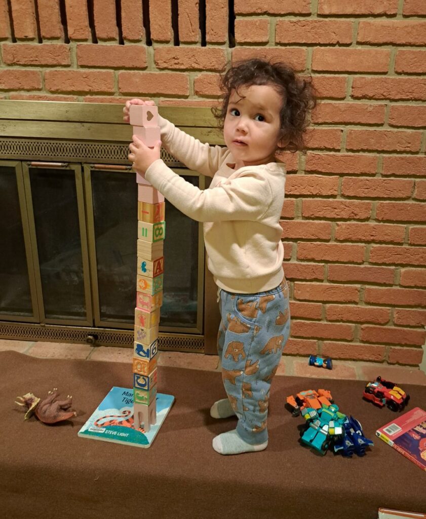 Leila stacking wooden blocks almost to her full height