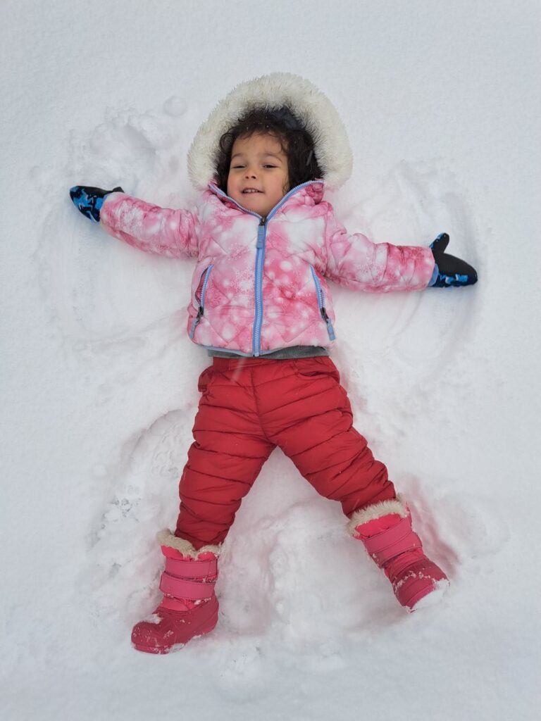 Little girl on her back making a snow angel